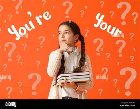Thoughtful little girl with books studying English grammar on orange ...