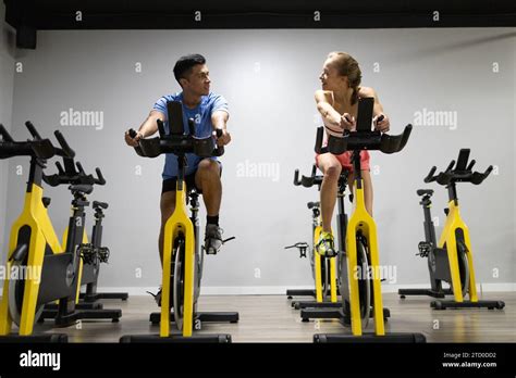 Two people engaged in a high-intensity workout on stationary bikes ...