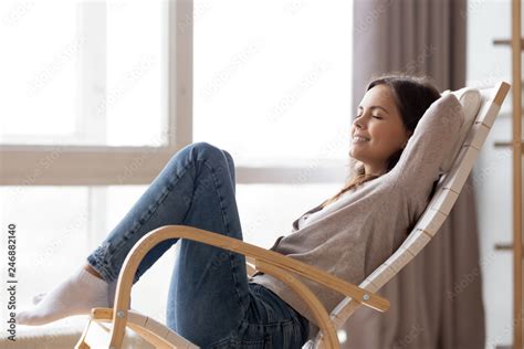 Relaxed calm young woman lounging sitting in comfortable wooden rocking ...