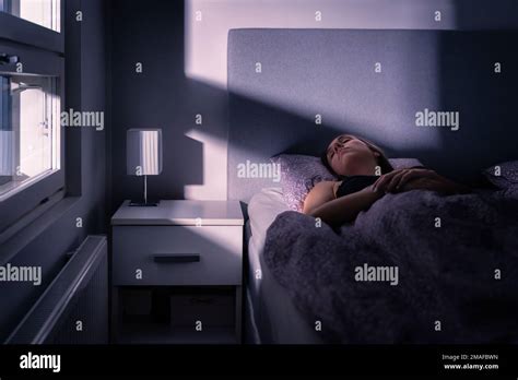 Sleeping woman in bed at night in dark bedroom. Person under blanket and cover. Person asleep ...