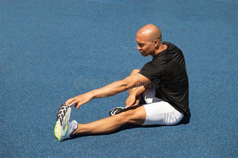 Athlete Stretching after Workout or Run on Sport Ground. Outdoors ...