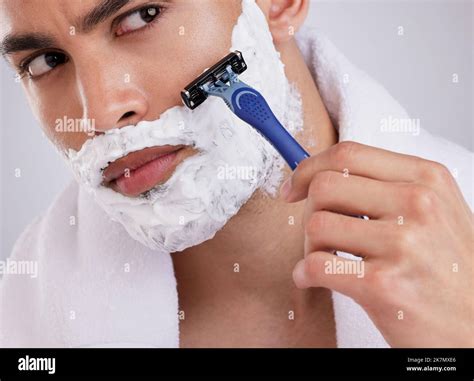 Go with the grain not against. a young man shaving his beard against a ...