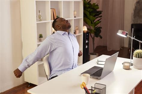 Premium Photo | Employee stretching at office desk at work tired african american office worker