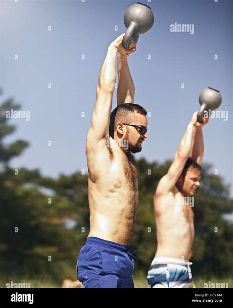 Two strong young men lifting heavy kettlebell weights Stock Photo - Alamy