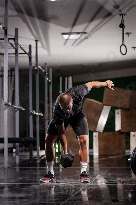 Muscular athlete lifting very heavy weights Man working out indoors ...