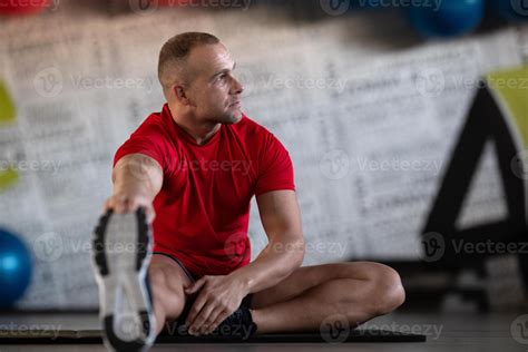 A fitness man stretches in the gym after an intense workout, focusing ...