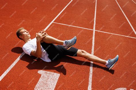 Premium Photo | An athlete is doing stretching exercises on the track ...