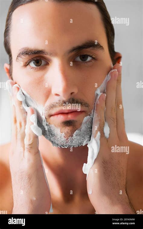 Portrait of a young man applying shaving cream on his face Stock Photo ...