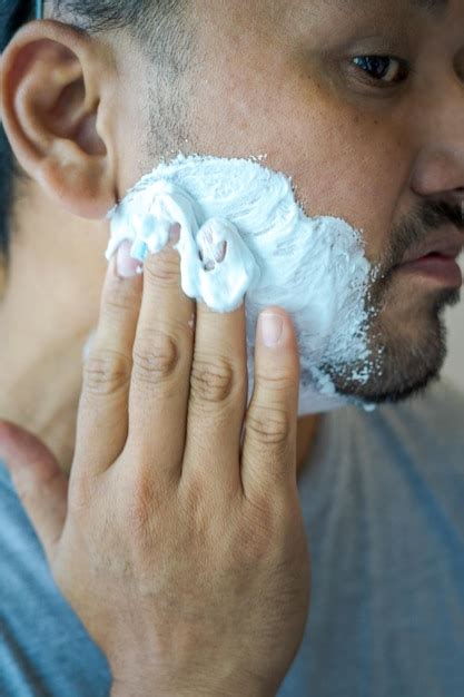 Premium Photo | Applying shaving cream on the face of an asian man