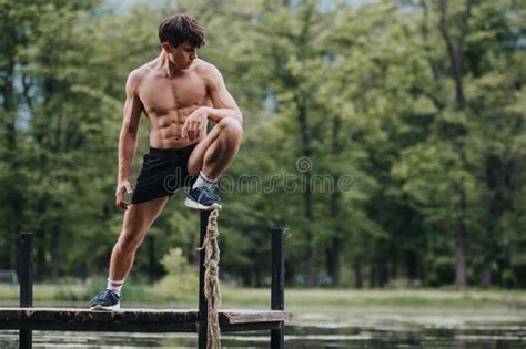 Young Man Exercising Outdoors on a Dock by the Lake in a Forested Area ...