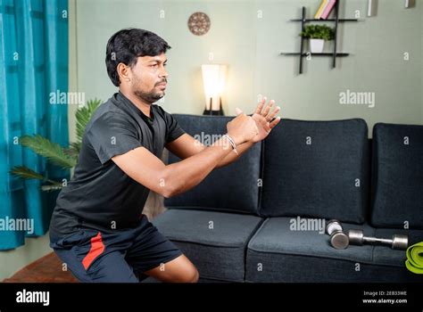 Young man busy in Squat exercise at home during coronavirus covid-19 lockdown - concept of ...