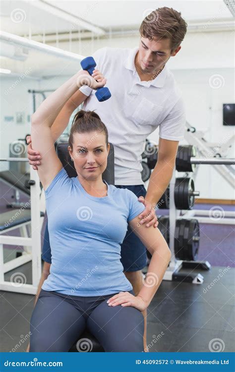 Personal Trainer Helping Client Lift Dumbbell Stock Photo - Image of ...