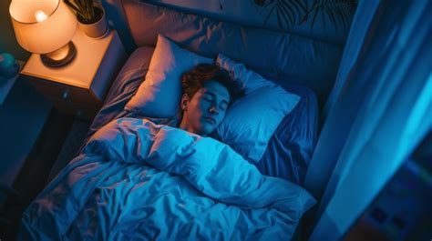 Handsome young man sleeping peacefully on a bed in his bedroom at night ...