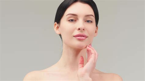 Close up beauty portrait of young woman with smooth healthy skin, she gently touches her face ...