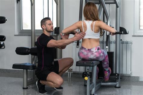 Premium Photo | Personal trainer helping client in gym