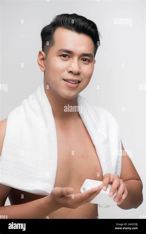 Happy man applying lotion after shave on face over white background ...