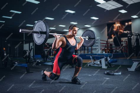 Premium Photo | Weight lifter doing squats with a barbell in gym