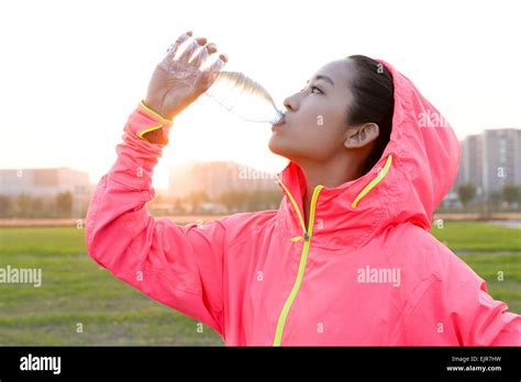 Young woman drinking water during exercise Stock Photo - Alamy